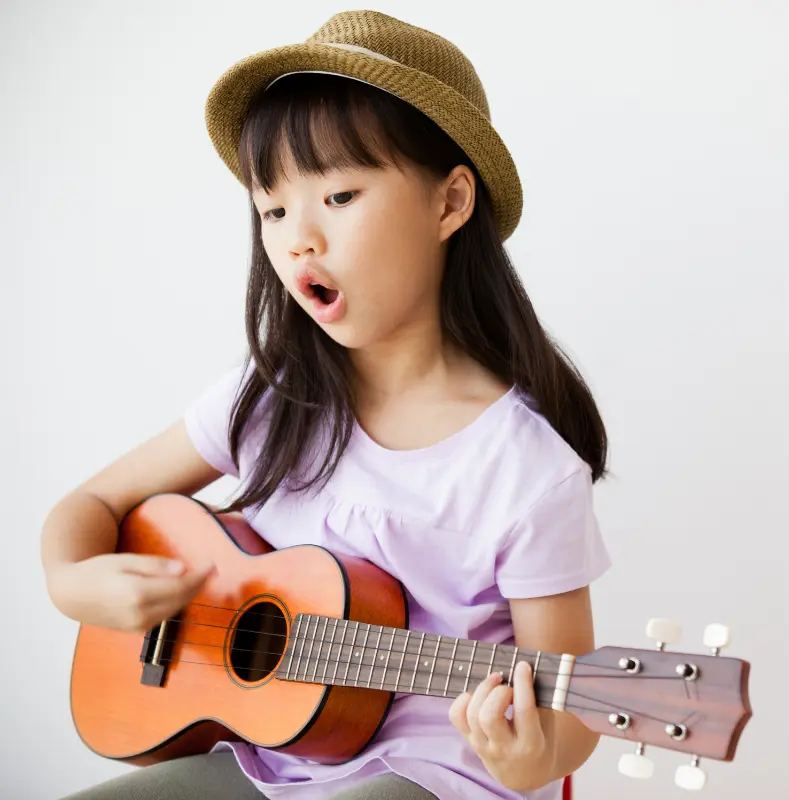 enfant qui joue une chanson au ukulélé et qui chante