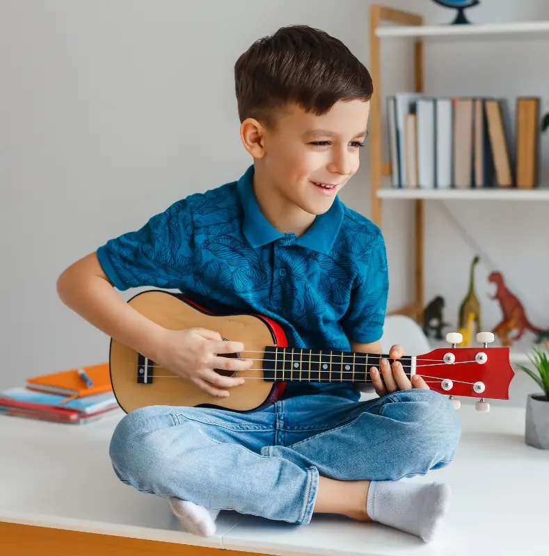 Garçon jouant ses premiers accords de ukulélé. c'est un instrument à choisir pour un enfant débutant ?