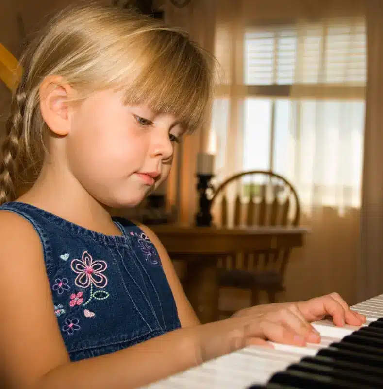Quel instrument choisir pour un enfant ? Fille concentrée jouant ses premières notes de piano.