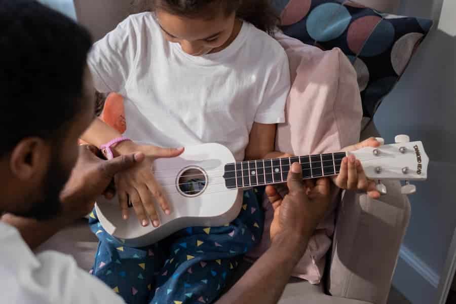 Un enfant apprend le ukulélé avec l’aide d’un parent