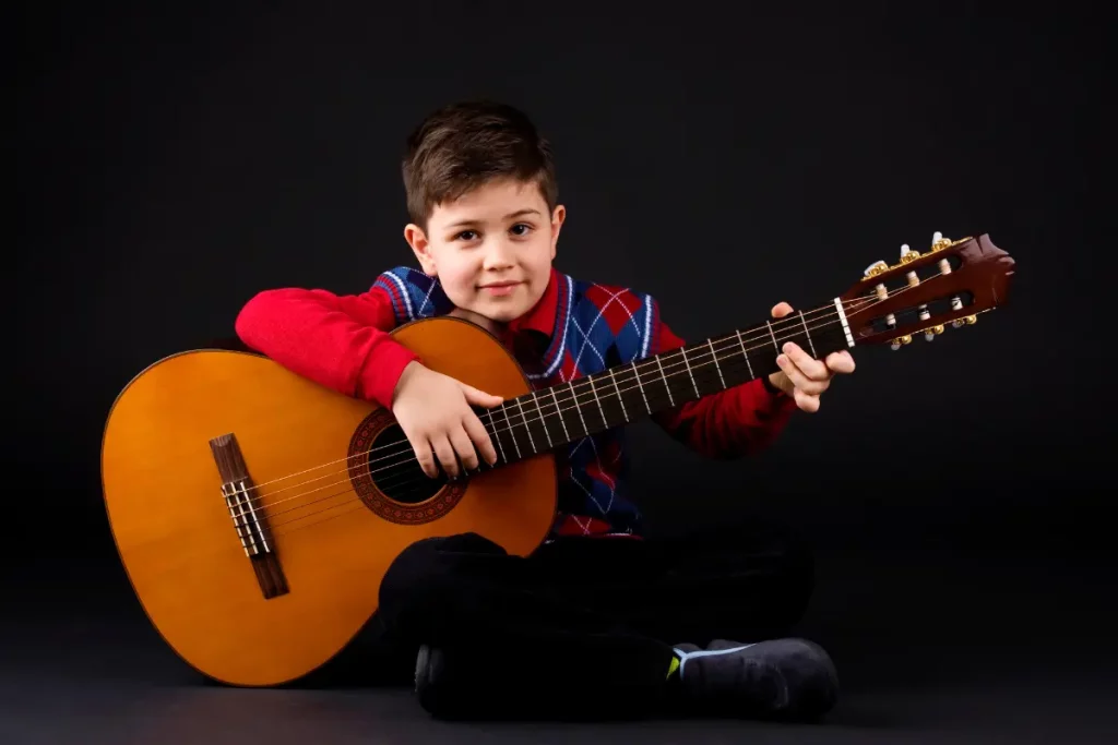 Un enfant met en évidence la  différence ukulélé guitare avec une guitare trop encombrante