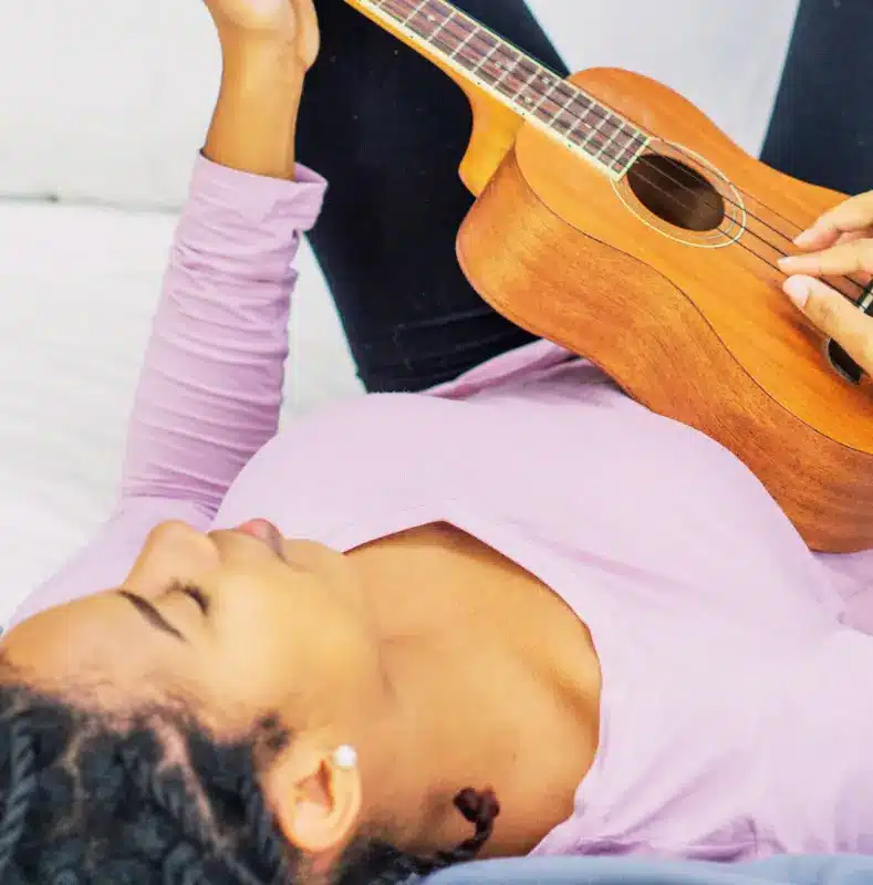 femme qui joue du ukulélé sur son canapé pour progresser rapidement